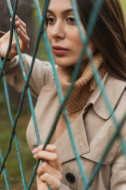 Portrait of charming female that standing near fence - Zdjęcie, obraz