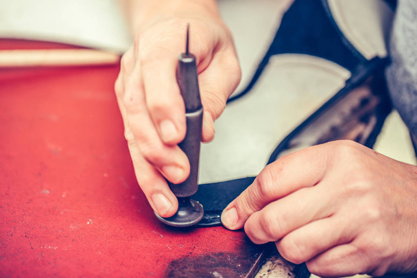 Erkek ayakkabıcı, el işi aletleri kullanarak deriyle çalışıyor. - Fotoğraf, Görsel