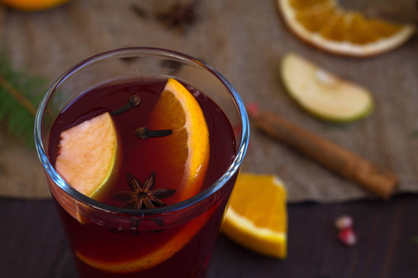mulled wine with slices of orange, apple and spices, cinnamon and anise star on a wooden background with winter decorations. top view. hot drinks of winter and autumn. copy space - Φωτογραφία, εικόνα