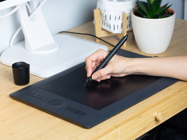 The designer draws on a graphic tablet at his workplace.  - Photo, Image
