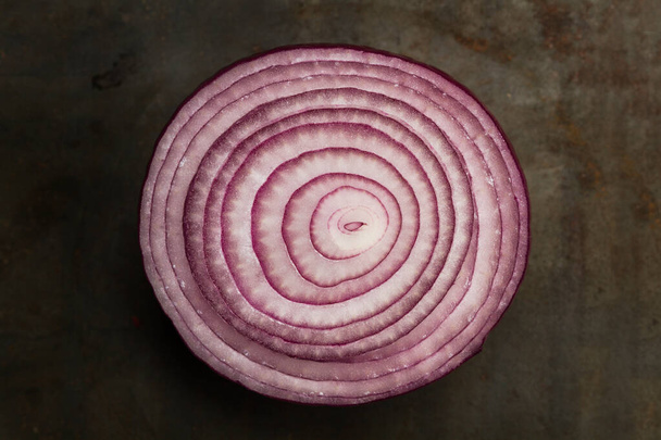 Slice of purple onion on a rusty metal table in a top view - Фото, зображення