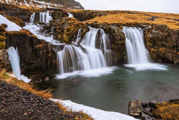 Słynna góra z wodospadami w Islandii, kirkjufell, zima na Islandii, lód i śnieg, refleksje, żółta trawa, natura, icelandyjski słynny krajobraz - Zdjęcie, obraz