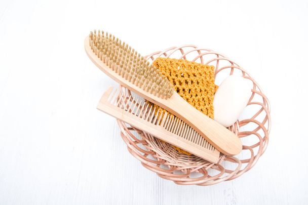 wooden comb, brush, soap, washcloth made of natural material in a basket on a gray background, eco friendly concept, spa, body care - Φωτογραφία, εικόνα