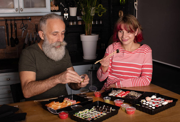 Kedves pár, akik jól érzik magukat, miközben otthon sushi tekercset esznek. - Fotó, kép