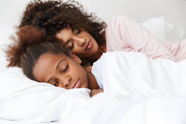 Image of african american woman and her little daughter sleeping - Фото, зображення