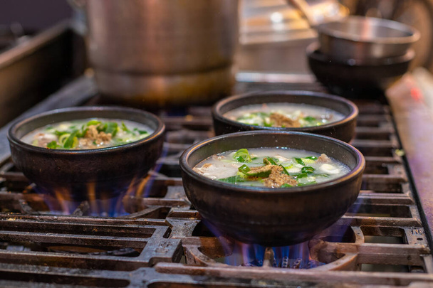 Kubki z zupą na niebieskim ogniu. Gorąca azjatycka zupa. Jedzenie z ulicy w kubku w ogniu. Egzotyczna zupa wysokopłomieniowa - Zdjęcie, obraz