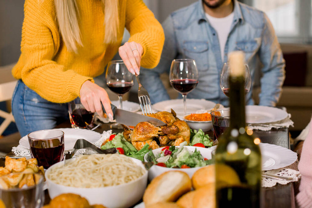 Cropped image of pretty young mother hands cutting turkey for family on thanksgiving dinner. Festive table with tasty food - Foto, imagen