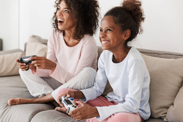 Image of american woman and little girl playing video games with - Photo, Image
