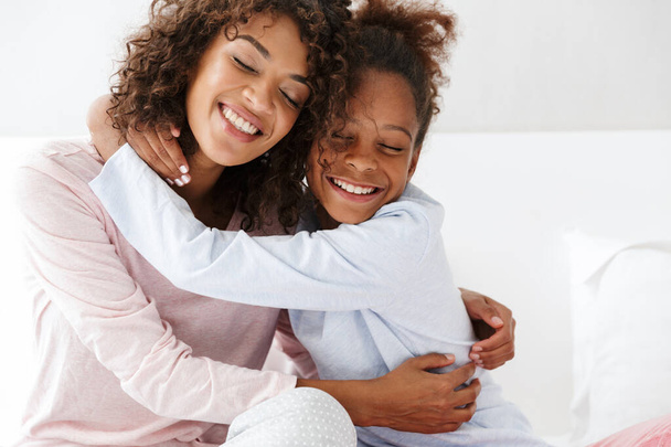 Image of african american woman and her little daughter hugging  - Fotó, kép