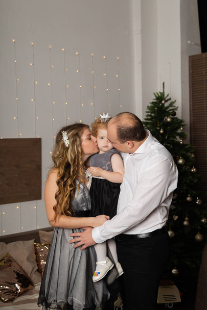 Hermosa familia feliz joven con un niño en sus brazos en la víspera de Año Nuevo. Año Nuevo 2020
. - Foto, imagen