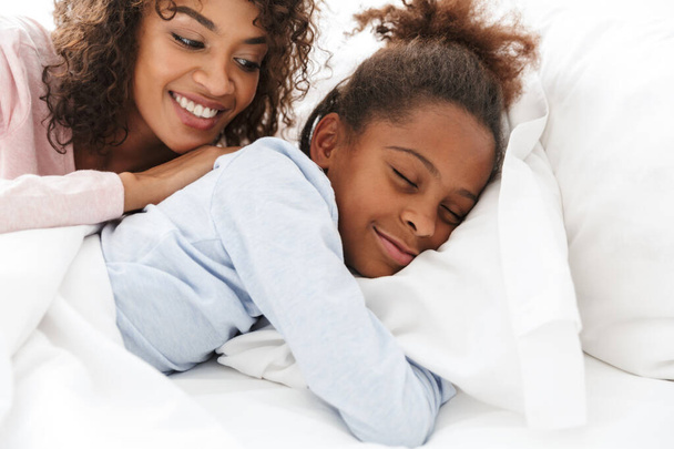 Image of african american woman and her little daughter sleeping - Zdjęcie, obraz