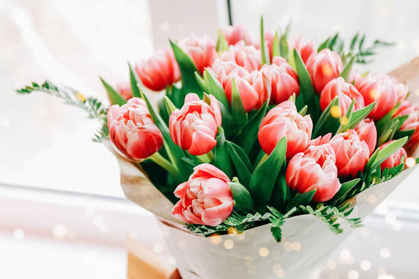 Hermoso ramo de tulipanes rosados envueltos en papel en alféizar de ventana
  - Foto, Imagen