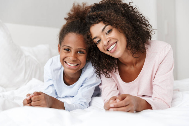 Image of african american woman and her little daughter lying in - Photo, Image