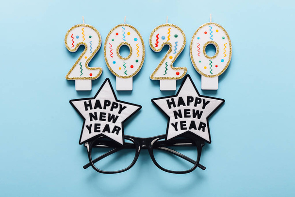 2020 velas y gafas de año nuevo sobre fondo azul. Feliz Año Nuevo concepto
 - Foto, imagen