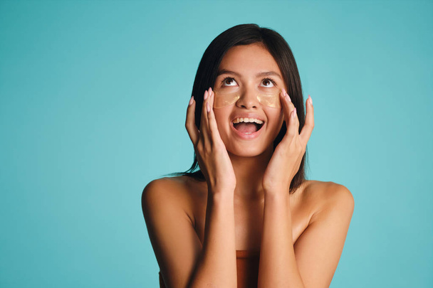 attraktive freudige asiatische Mädchen mit Flecken unter den Augen glücklich posiert über bunten Hintergrund - Foto, Bild