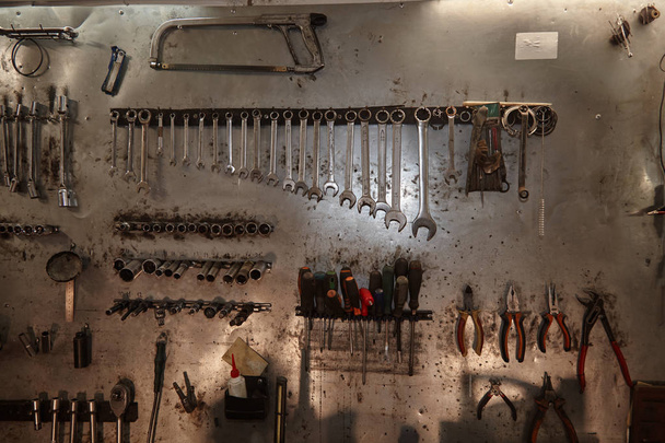 Workshop scene. Image of old tools hanging on wall in workshop. Vintage retro garage styl - Photo, Image