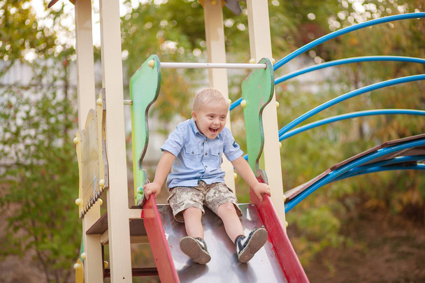 Každodenní život dítěte se zdravotním postižením. Chlapec s Downovým syndromem si hraje na hřišti. Chromozomální a genetická porucha u dítěte. - Fotografie, Obrázek