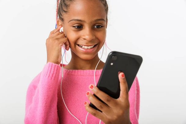 Image of focused african american girl holding cellphone and earphones - Zdjęcie, obraz