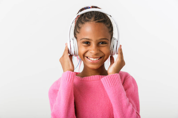 Image of pleased african american girl listening music with headphones - Zdjęcie, obraz