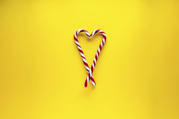 Coeur composé de bonbons sur fond jaune. Pose plate
.  - Photo, image
