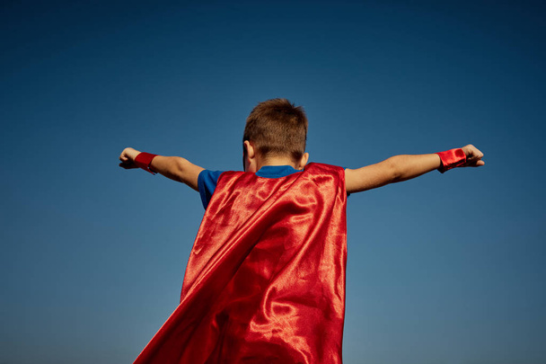 Super hero child (boy) against blue sky - Foto, afbeelding