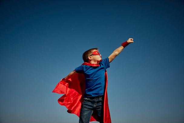 Criança super-herói (menino) contra o céu azul
 - Foto, Imagem