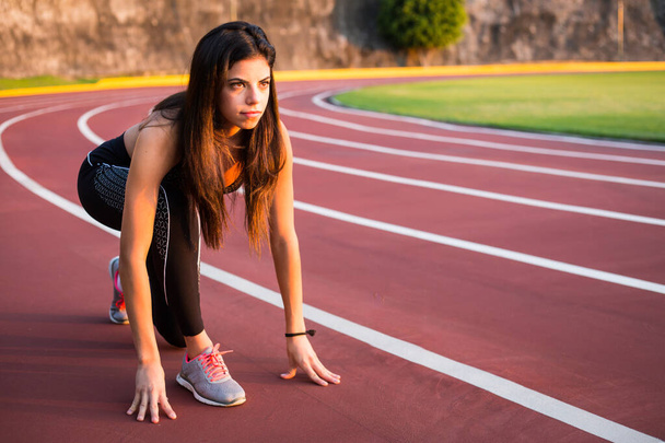 Corredor mujer joven se prepara para correr en pista de atletismo
 - Foto, imagen