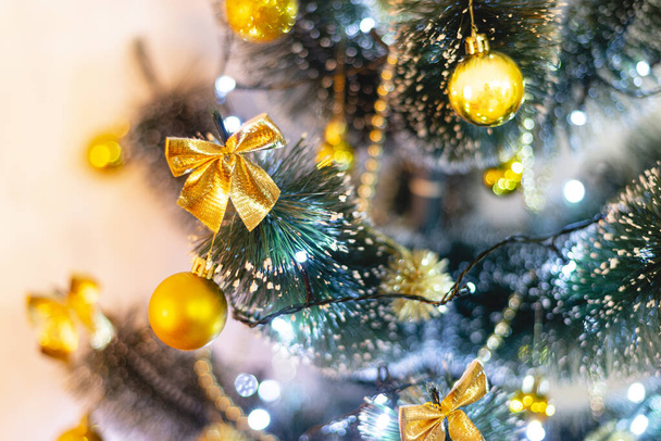 Detail van kunstmatige kerstboom met verlichting en gouden ornamenten. Focus op de voorgrond. - Foto, afbeelding