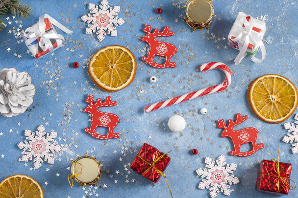 Christmas and New Year pattern from snowflakes, orange, cones, gifts and deers on a blue background with stars. Christmas, winter, new year concept. Flat lay, top view, copy space - Fotografie, Obrázek