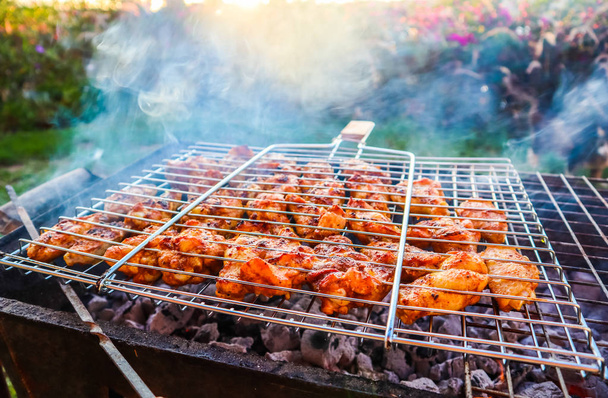 Cucinare spiedini di pollo alla griglia in giardino al tramonto
 - Foto, immagini