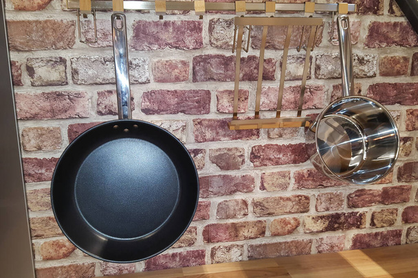 Panelas fogão pendurado na parede de tijolo da cozinha
 - Foto, Imagem