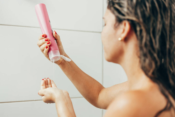 Young woman washing hair with shampoo in the shower - Foto, afbeelding