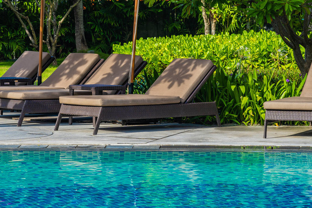 Hermoso paraguas y silla alrededor de la piscina al aire libre en caliente
 - Foto, Imagen