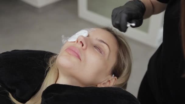 Ammattimainen kosmetologi kauneushoitolassa käyttää silmäripsien laminointigeeliä asiakkaan silmäripsiin
. - Materiaali, video
