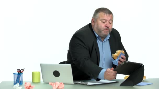 Overweight uomo d'affari mangiare hamburger sul suo posto di lavoro
. - Filmati, video