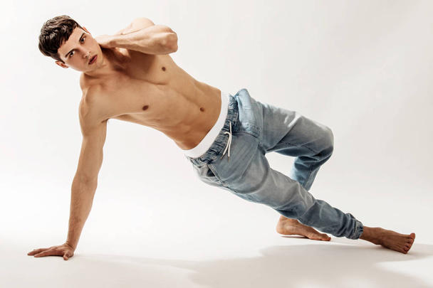Muscle strong beautiful stripped male model in denim jeans on white isolated font background with shadow - Fotó, kép