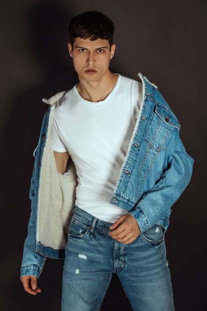 Muscle strong beautiful stripped male model with white t-shirt in denim jeans and denim jacket on black isolated font background - Foto, Bild