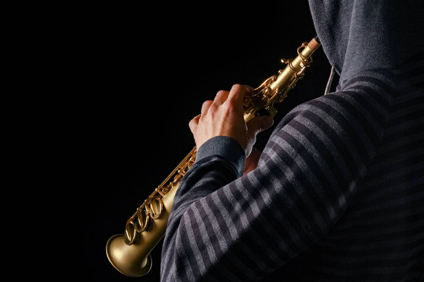 soprano saxophone in the hands of a guy on a black background - Φωτογραφία, εικόνα