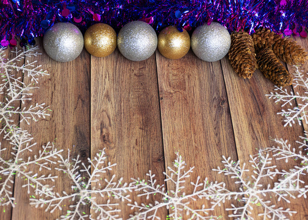 Подарки упакованы в крафтовую бумагу и завязаны атласной лентой с рождественскими игрушками и фиолетовой мишурой на деревянном фоне. Сюрприз для праздника. Декор для елки
 - Фото, изображение