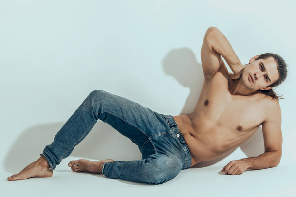 Muscle strong beautiful stripped male model in denim jeans on white isolated font background with shadow - Foto, immagini