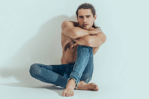 Muscle strong beautiful stripped male model in denim jeans on white isolated font background with shadow - 写真・画像