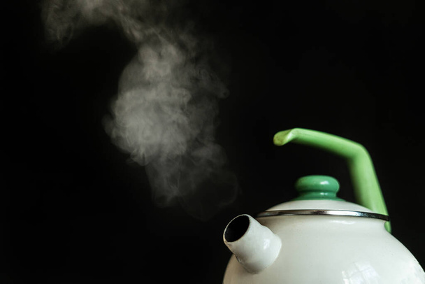 чайник з гарячою киплячою водою і пара виходить з нього на темному фоні
 - Фото, зображення
