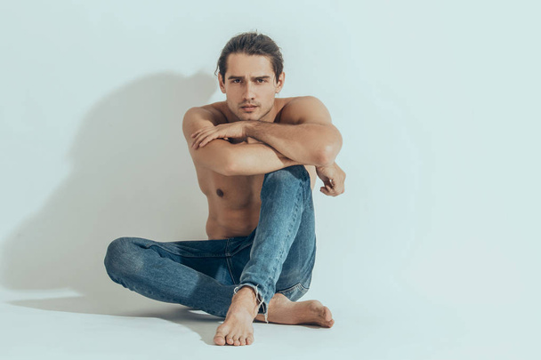 Muscle strong beautiful stripped male model in denim jeans on white isolated font background with shadow - 写真・画像