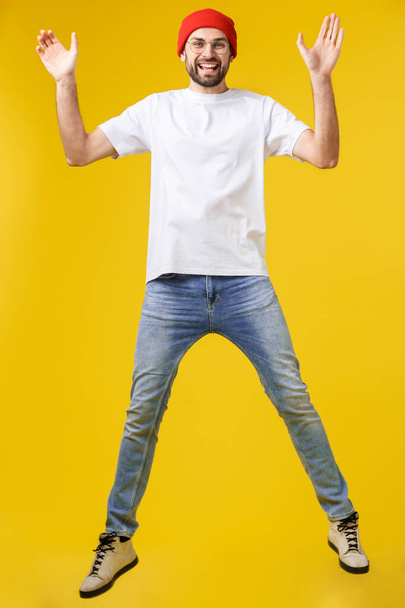 若いカジュアルな男が黄金の背景で喜びのためにジャンプ - 写真・画像