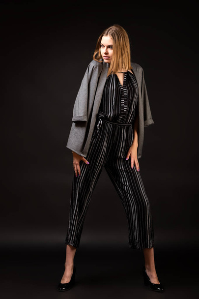 Concept Business Woman. Attractive woman in fashionable business clothes in a striped overalls and knitted overalls posing in a studio shot. Portrait of a modern successful woman - Photo, Image