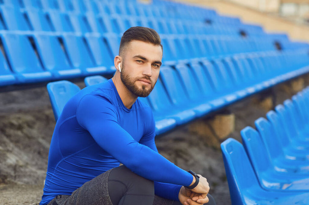 A guy in sportswear is sitting in the stadium after training. - Фото, изображение