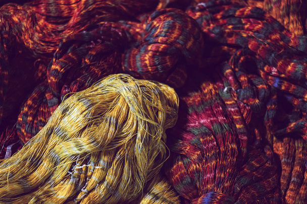 織物のための赤と黄色のカラータイ染料シルク糸のクローズアップ、タイの泥生地、天然素材から染色されたシルク糸 - 写真・画像