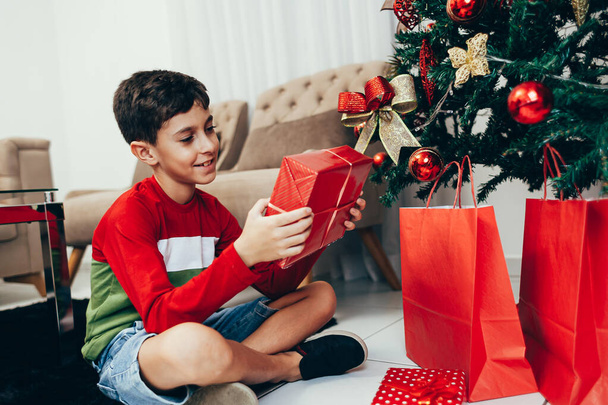 Happy and funny small boy with gifts and Merry Christmas tree. Merry Christmas and New Year concept. - Foto, imagen
