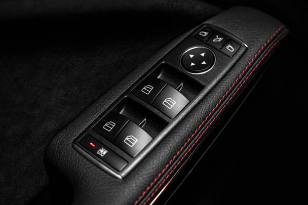 Feche um painel de controle de porta em um novo carro moderno. Apoio do braço com painel de controle da janela, botão de bloqueio da porta e controle do espelho
 - Foto, Imagem