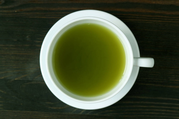 Вид зверху яскраво-зеленого кольору Гаряча мача зелений чай на темно-коричневому дерев'яному столі
 - Фото, зображення